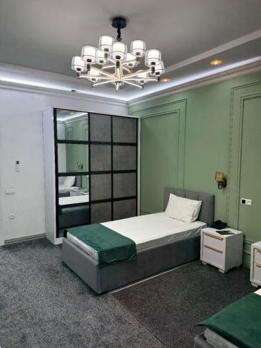 a bedroom with a large bed and a chandelier at GRAND SARBON HOTEL in Qarshi