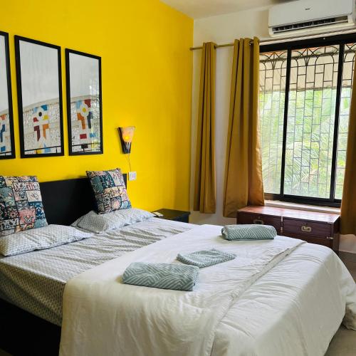 a bedroom with a large bed with yellow walls at Cozy Corner - Tropical 2BHK pool pad in Varca