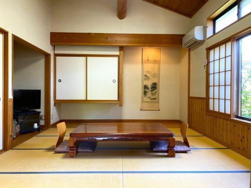 a living room with a wooden table and a tv at Ryuuei in Kawazu