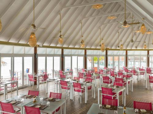 a dining room with tables and red chairs at Sun Siyam Vilu Reef - 24 Hours All-Inclusive with Free Transfer in Dhaalu Atoll