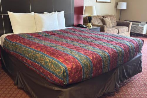 a large bed in a hotel room with a couch at Coratel Inn & Suites by Jasper Santa Fe OKC in Oklahoma City