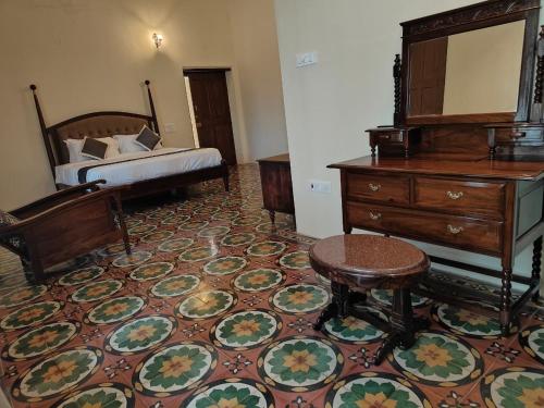 a bedroom with a bed and a dresser and a stool at The Estate Bay by Z Vacations in Gonikoppal