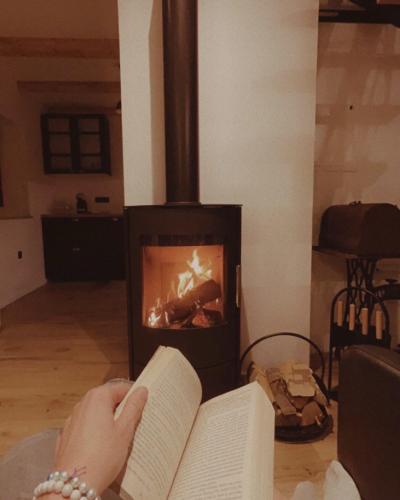 a person reading a book in front of a fireplace at Riverside House Krka in Zagradec