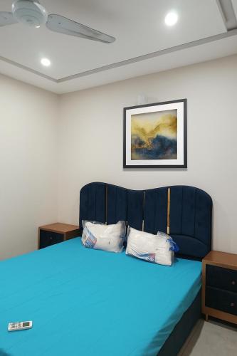 a blue bed in a room with a picture on the wall at Luxe 1 Bedroom Apartment in Doha emporium B-17, Margalla views in Islamabad