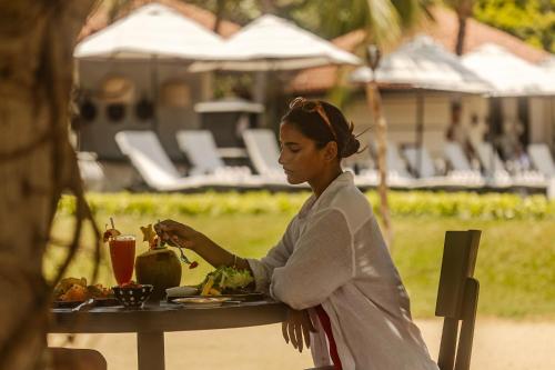 a woman sitting at a table with a plate of food at Sun Siyam Pasikudah in Pasikuda