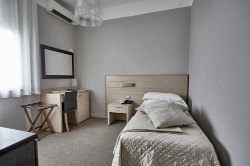 a bedroom with a bed and a desk and a mirror at Rouge Hotel International in Milano Marittima