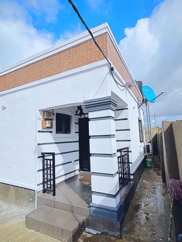 a white house with a black door and a staircase at Zeal City Dwellin in Loburo