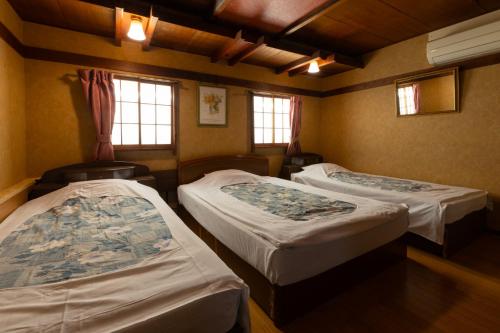 a room with two beds and two windows at Hotel Daiki in Osaka