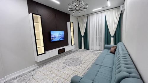 ein Wohnzimmer mit einem blauen Sofa und einem Fernseher in der Unterkunft Шикарная 2х комнатная квартира ЖК БИРЛИК in Schymkent