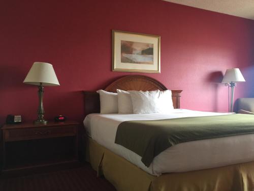 a bedroom with a large bed with a red wall at Baymont Inn & Suites by Wyndham Holbrook in Holbrook