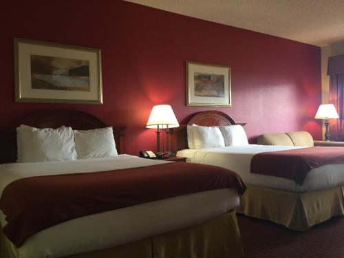 two beds in a hotel room with red walls at Baymont Inn & Suites by Wyndham Holbrook in Holbrook
