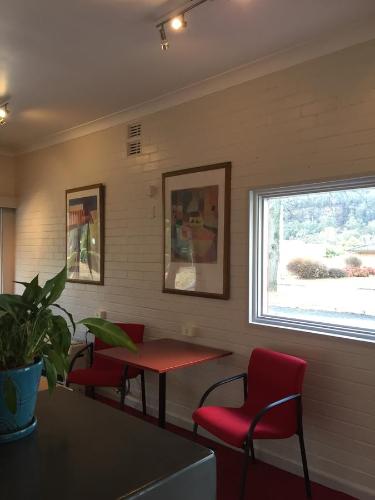 a waiting room with red chairs and a table and a window at Lithgow Valley Motel in Lithgow