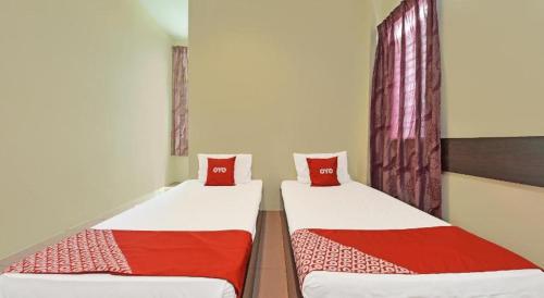 two beds in a room with red pillows at SPOT ON 91178 Motel Impian in Seri Manjung