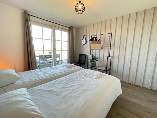 a bedroom with two white beds and a window at De Tuinkamer in Egmond aan den Hoef