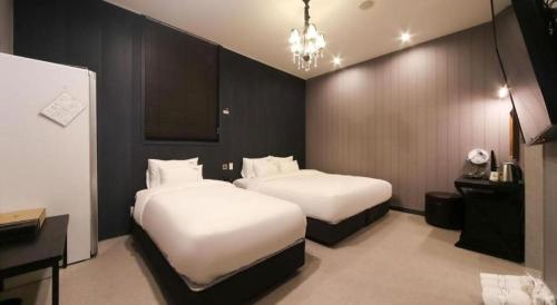 a hotel room with two beds and a chandelier at Hotel Seowa in Gimhae