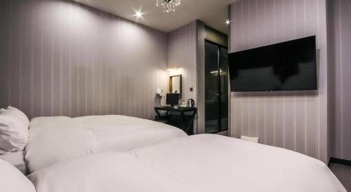 a bedroom with two white beds and a flat screen tv at Hotel Seowa in Gimhae