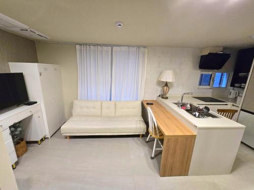 a kitchen with a sink and a couch in a room at Roome House in Seoul