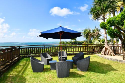 a group of chairs and an umbrella and the ocean at THE BAY in Trou dʼ Eau Douce
