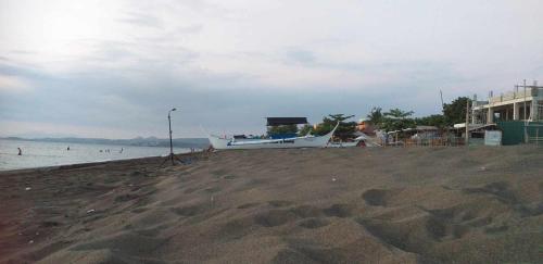 a boat sitting on a beach with the water at Kua's Pad Batangas Room in Lian