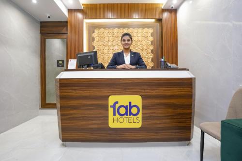 ムンバイにあるFabHotel Prime Palm Grove - Nr BKCの女がフロントデスクの後ろに立っている