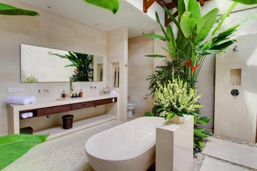 a bathroom with a toilet and a sink with plants at Nyaman Villas in Seminyak