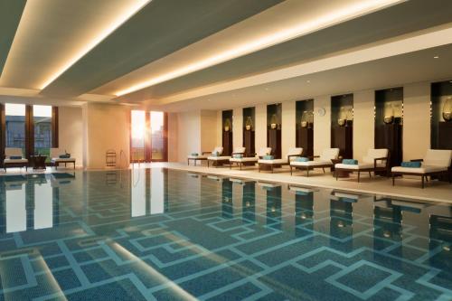 Midtown Shangri-La, Hangzhou - around 5 minutes walking distance to West Lake في هانغتشو: مسبح الفندق مع الكراسي والطاولات