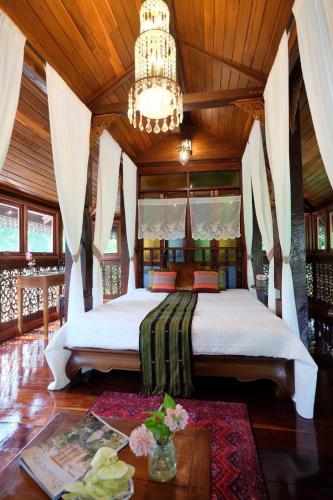 a bedroom with a large bed with a chandelier at เรือนไทยพราวพิมาน Proudpiman Thai Heritage House in Ban Bang Toei (1)