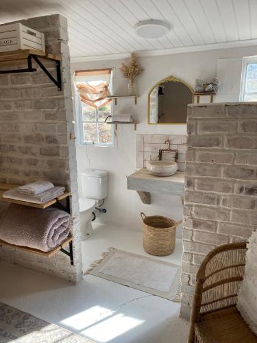a bathroom with a sink and a brick wall at Soutbos Cottages in Laingsburg