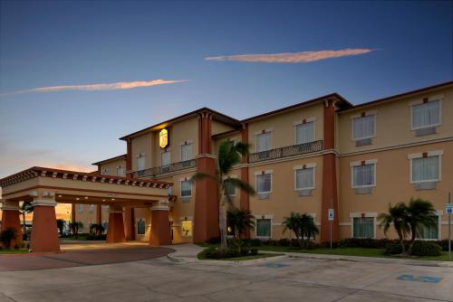 a large building with palm trees in front of it at Super 8 by Wyndham Hidalgo at La Plaza Mall & Mcallen Airport in Hidalgo