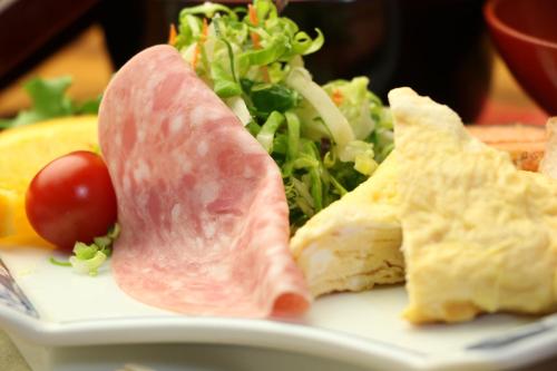a plate of food with ham and a salad at Sun Flower City Hotel in Setouchi