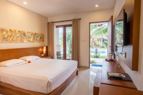 um quarto com uma cama grande e uma televisão em Sinar Bali Hotel em Legian