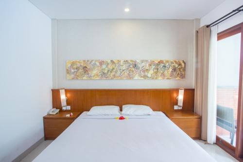 a bedroom with a large white bed and a window at Hotel Sinar Bali Legian in Legian