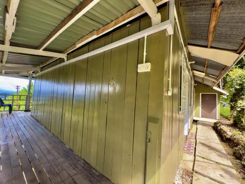a covered porch of a house with a green wall at Rustic Bed & Breakfast in Ranau