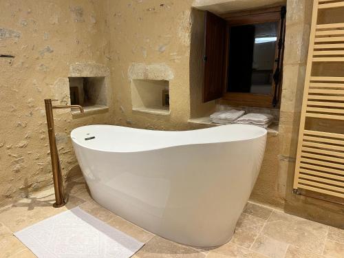 a large white bath tub in a stone bathroom at Seigneurie du Bois Moreau in Durtal