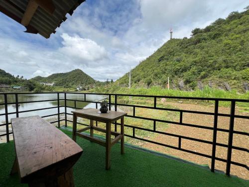a table and bench on a balcony overlooking a river at Homestay Quản Thanh in Loung Co