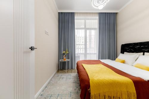a bedroom with a large bed and a window at Апартаменты возле Хан-Шатыра и Ботанического Сада in Astana
