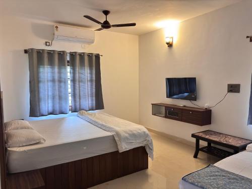 a small room with a bed and a flat screen tv at Matsyaangana Homestay in Sringeri
