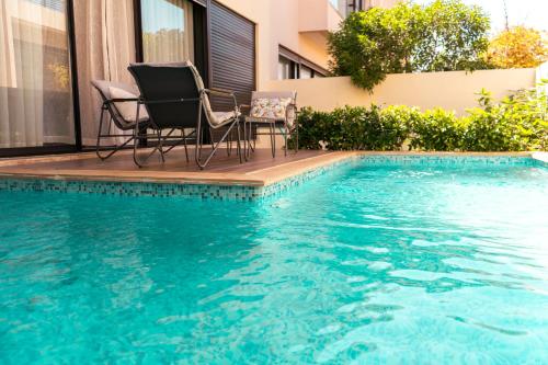a swimming pool with two chairs and a table next to it at Villa 4-Bedroom with Private Pool & Rooftop Sea View in Tamaris in Casablanca