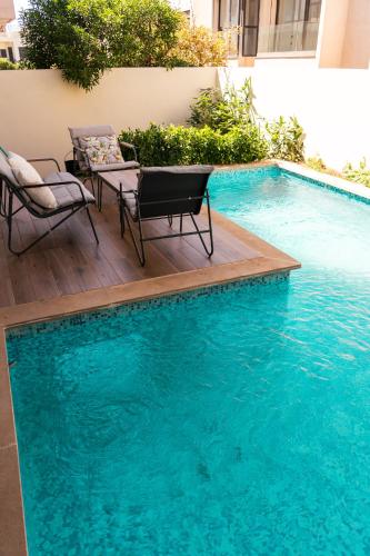 a swimming pool with two chairs and a table next to it at Villa 4-Bedroom with Private Pool & Rooftop Sea View in Tamaris in Casablanca