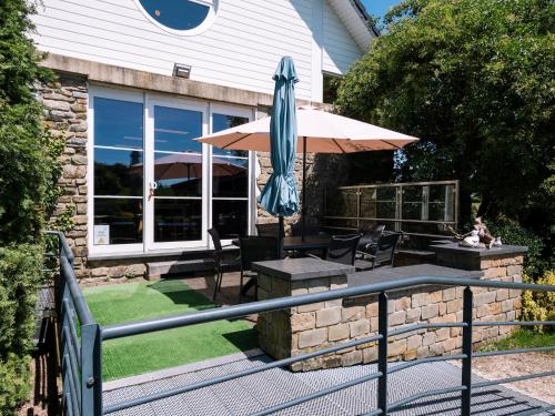 a patio with an umbrella and a table and chairs at Moderscheid Cottage with Spa in Amblève
