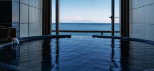a swimming pool with a view of the ocean at Atagawakan in Higashiizu