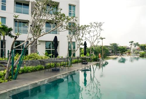 a swimming pool with tables and chairs next to a building at Lush Lakeside - Citra Luxury Apartments in Jakarta