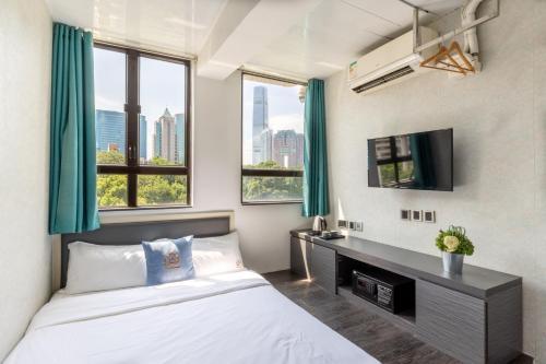 a bedroom with a bed and a desk and windows at Atlas Hostel & Backpackers in Hong Kong