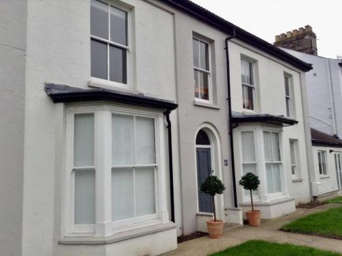 a white house with white windows and potted plants at Golden Triangle Rooms in Norwich