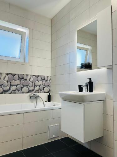 a white bathroom with a sink and a bath tub at Apartment Richy Brasov in Braşov