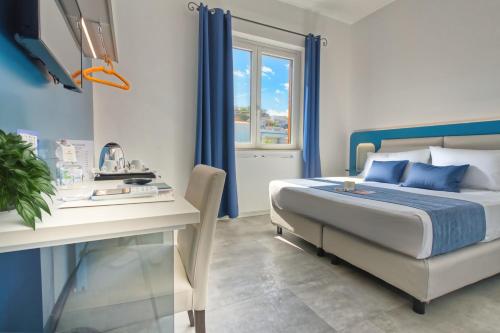 a bedroom with a bed and a desk and a window at Hotel La Battigia in Alcamo Marina