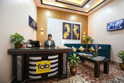 a woman sitting at a reception desk in a hotel lobby at FabHotel Geeta Bhawan in Ayodhya
