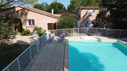 a swimming pool with a white fence next to a house at Gite 5 pers en Provence avec grand jardin & piscine partagés - 5 people holiday home with shared swimming pool & garden in Provence in Cornillon-Confoux
