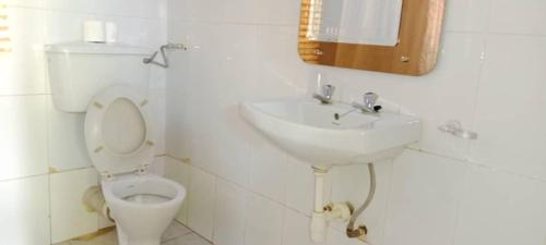 a white bathroom with a toilet and a sink at Gorilla African Guest House in Entebbe
