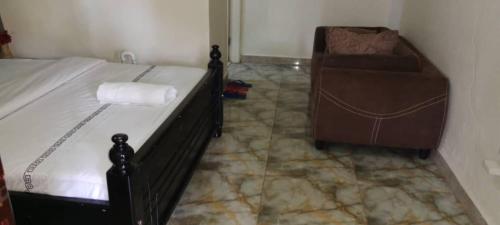 a bedroom with a bed and a chair in a room at Gorilla African Guest House in Entebbe